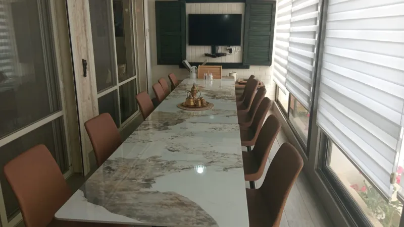 חדר האוכל המשפחתי עם שולחן שיש ארוך, כיסאות עור וטלוויזיה