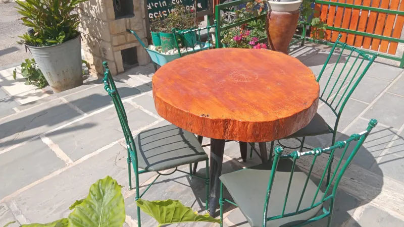 שולחן עץ עגול וכיסאות ברזל ירוקים בחצר