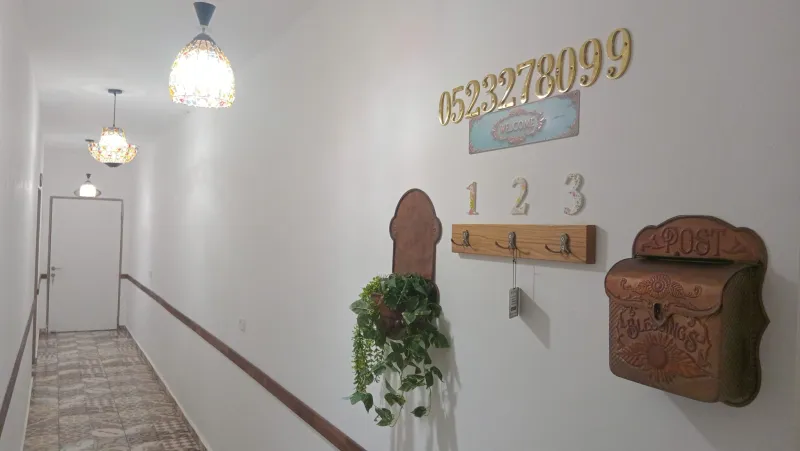 קיר הכניסה עם מספרי הסוויטות, תיבת דואר עתיקה ומנורות צבעוניות